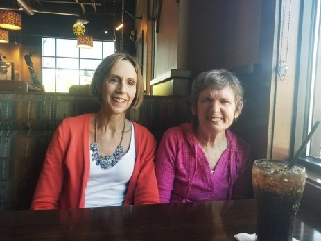 Maryann and her sister Cathy McIvor smiling sitting at a restaurant booth