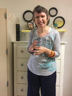 Maryann smiling and standing in front of a dresser