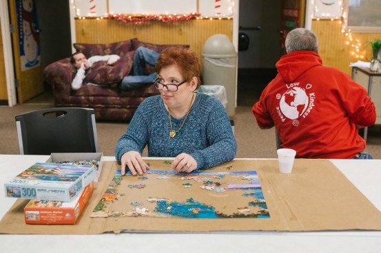 Pauline sitting at a table working on a jigsaw puzzle